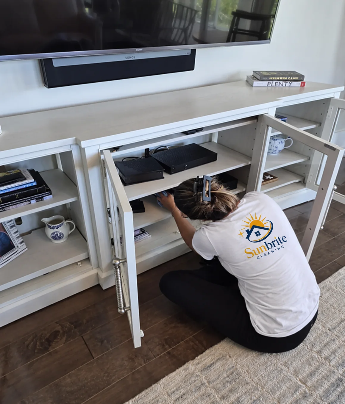 Sunbrite Cleaning LLC team member cleaning inside a white TV media console cabinet